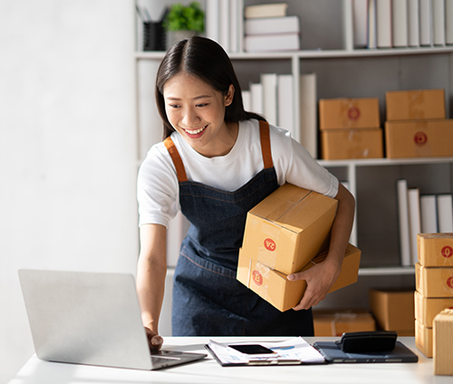 young woman with boxes checking computer