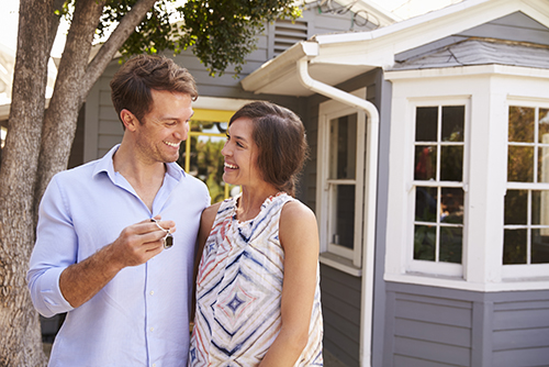 couple with keys in front of house