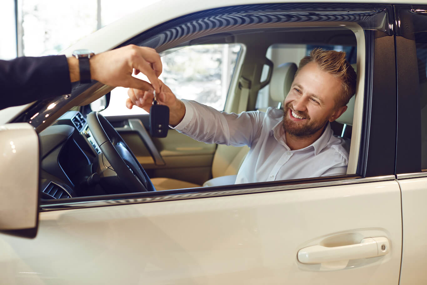 a man receives keys to his new car and drives off the dealership lot